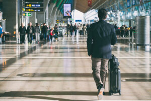 スーツケースを引いて空港の搭乗口へ向かう男性
